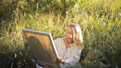 creative beautiful female artist paints a picture with acrylic paints outdoors in the forest