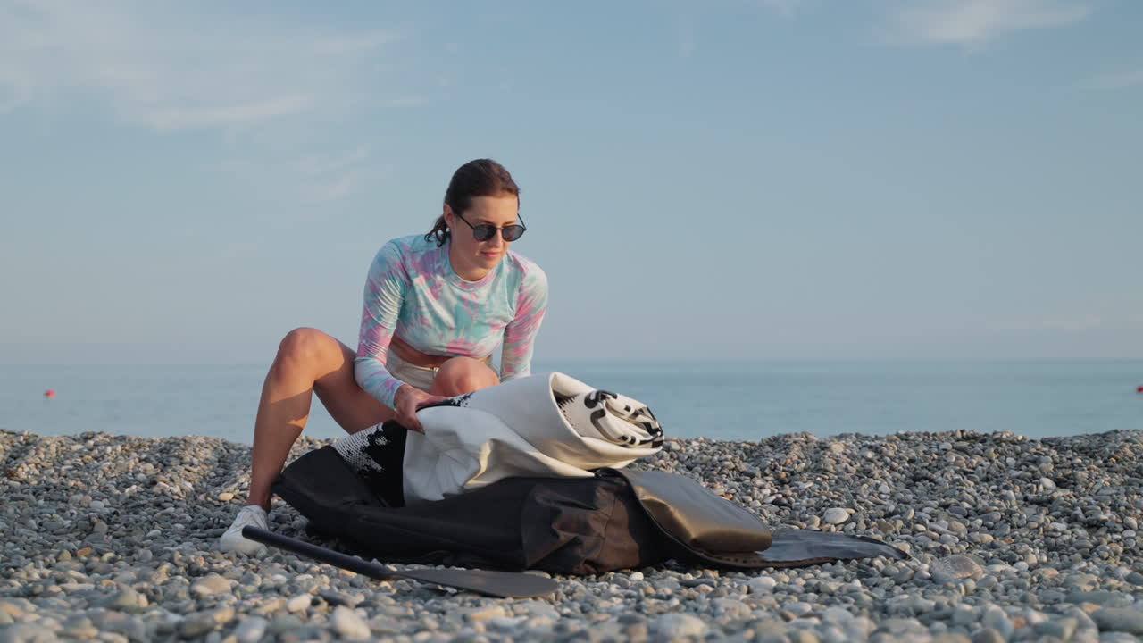 mujer preparando un paddleboard en una playa