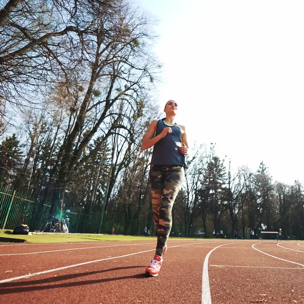 Summer outdoors training. Athlete woman starting running on running track. Beautiful girl doing exercises.