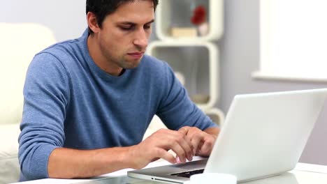 Cute-focused-man-typing-on-his-notebook