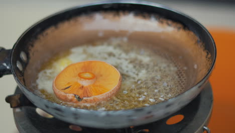 Putting-mushroom-on-the-frying-pan-at-the-camping