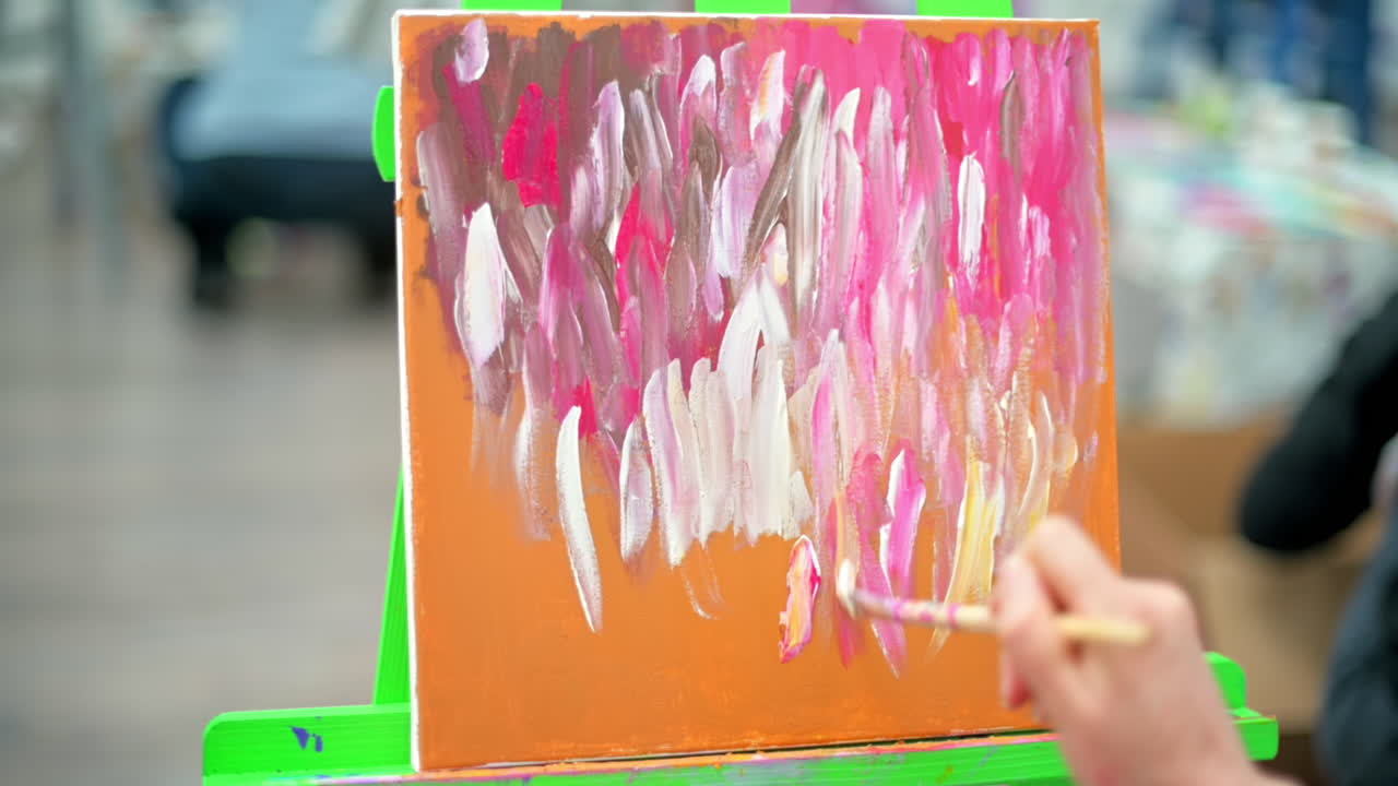A woman painting a picture using a brush in a studio. Slow motion