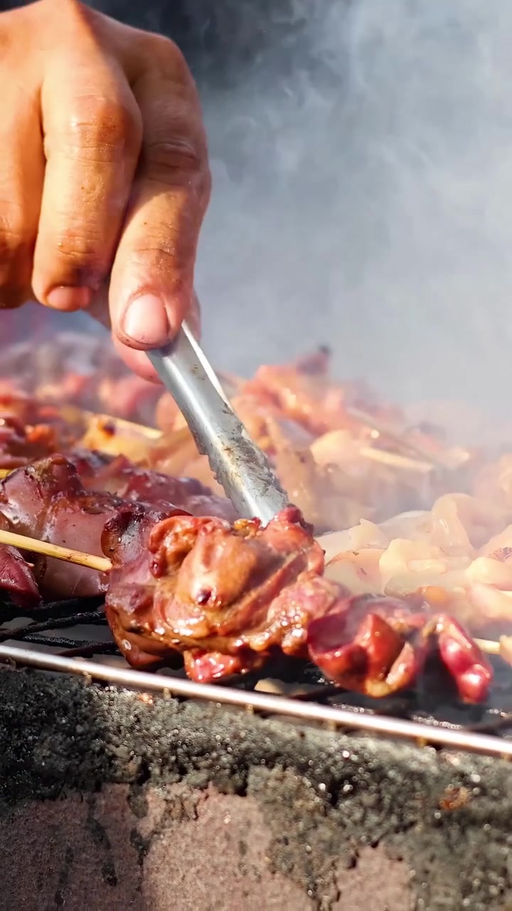 Olika sorters kött grillas över öppen eld vid ett gatustånd