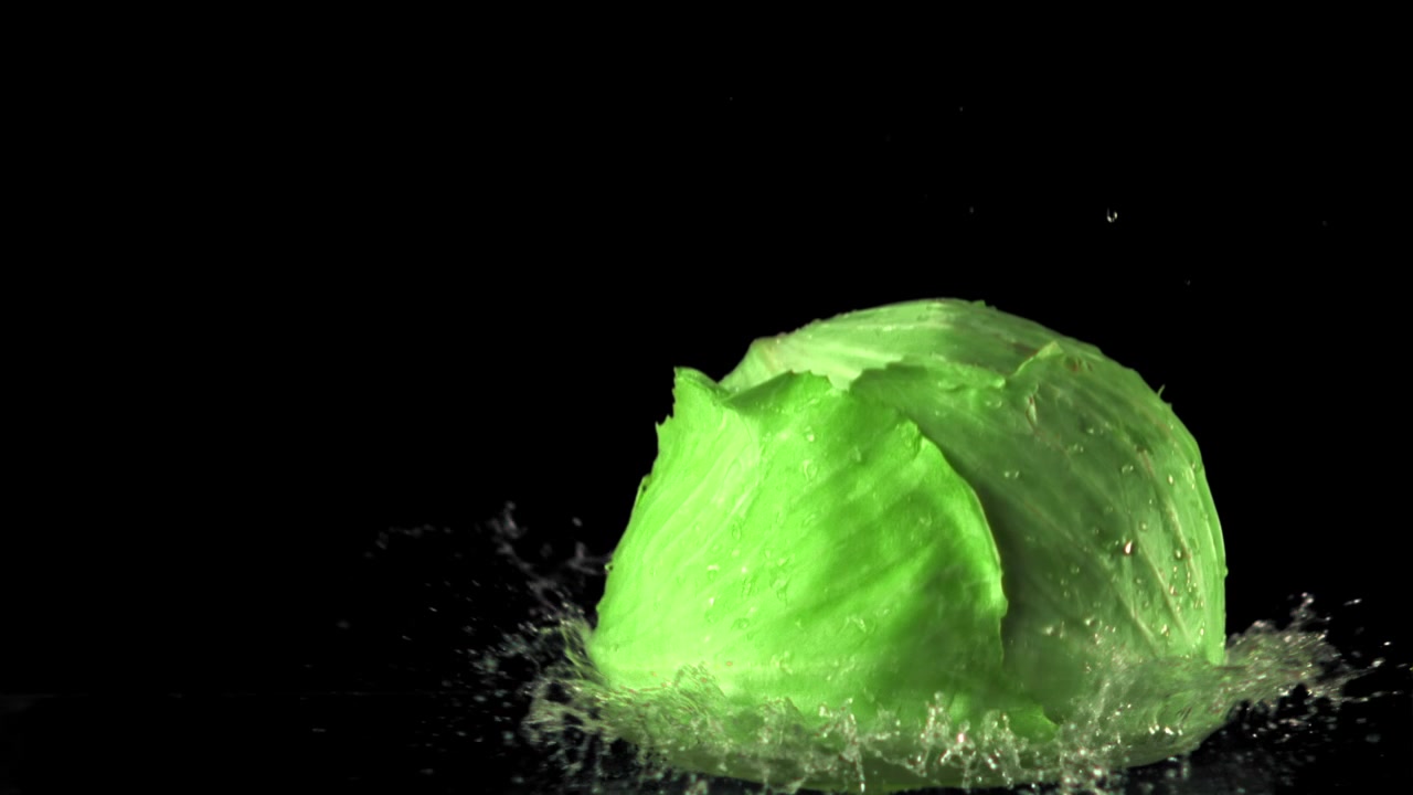 Fresh Green Cabbage Splashing into Water in Slow Motion