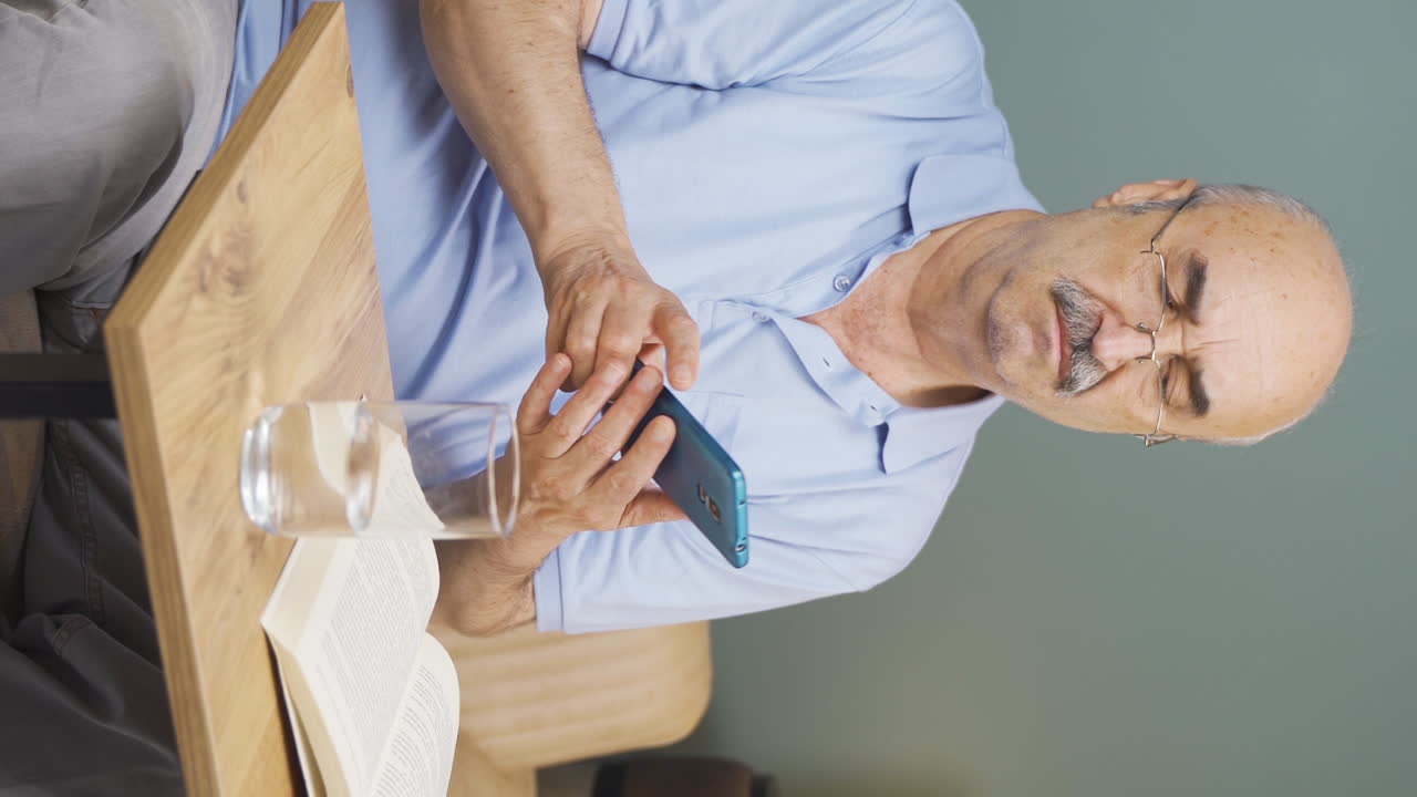 들어오는 전화 메시지에 화를 내고 화를 내는 노인의 수직 비디오입니다.