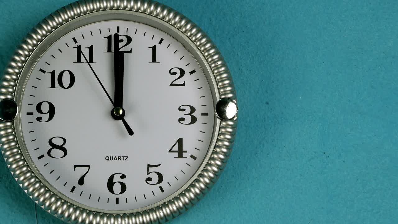 Quartz wall clock with second hand runs clockwise. The clock shows twelve o'clock.
