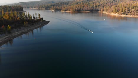 Aerial-shot-of-blue-lake-with-single-boat-speeding-through-the-water