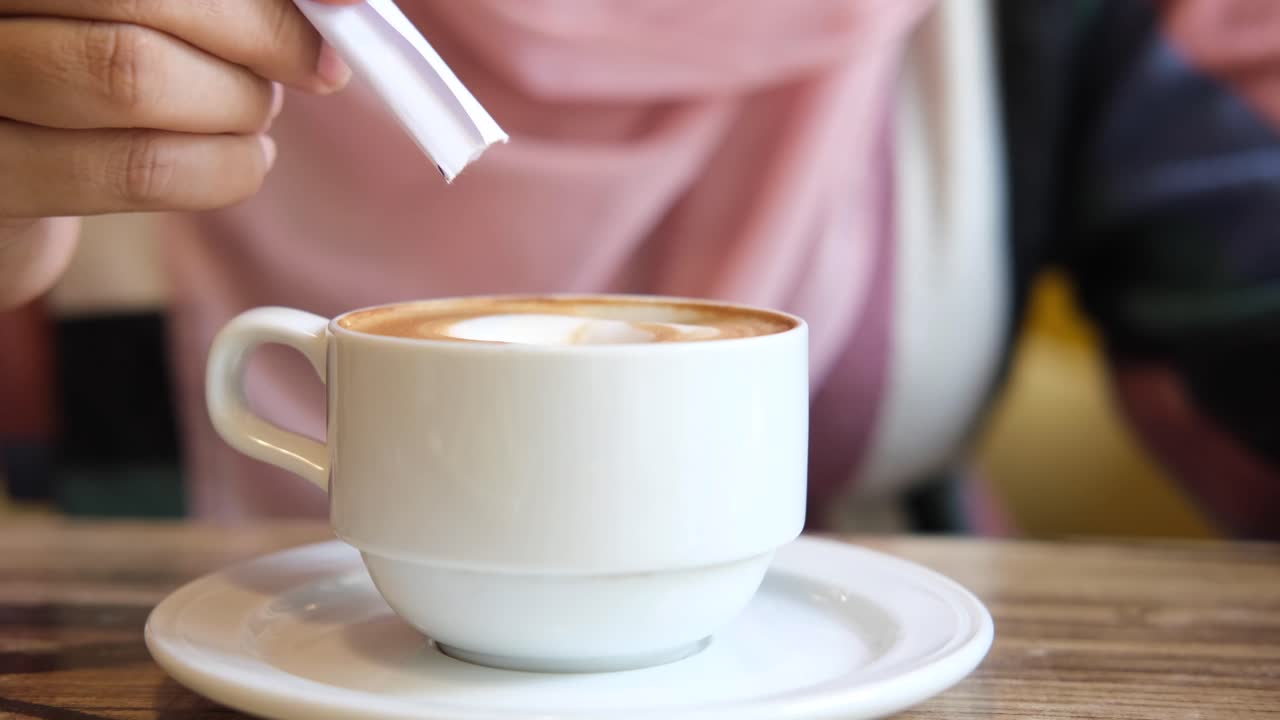 mujer añadiendo azúcar a su latte
