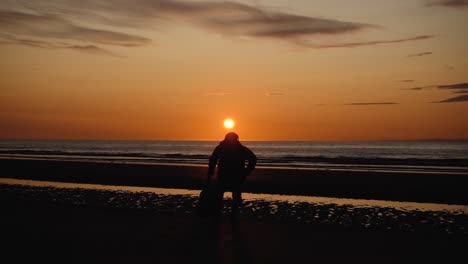 hombre corriendo con guitarra en la playa de arena trasera al atardecer-6