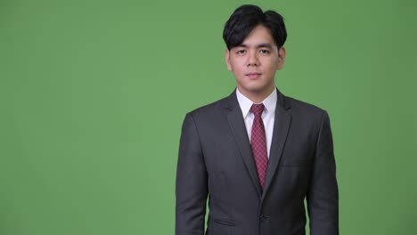 joven y guapo hombre de negocios asiático mostrando algo