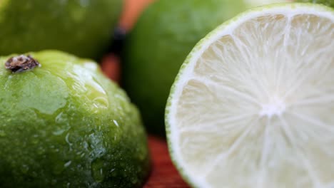 fresh green lime lemon on wooden cutting board, close-up pan