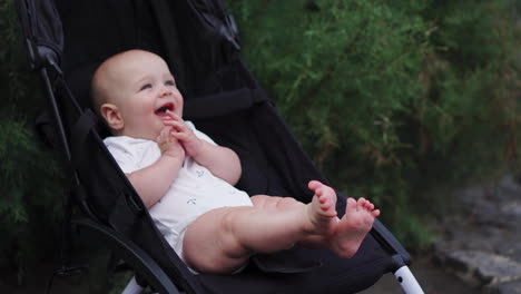 a smiling baby sits in a stroller and laughs