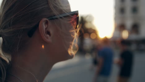 mujer con gafas de sol mirando a la distancia durante la puesta de sol