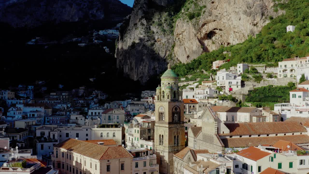 Volando verso la Cattedrale di Sant'Andrea Apostolo ad Amalfi. Vista aerea con drone dell'architettura storica italiana sulla Costiera Amalfitana al sole della sera.