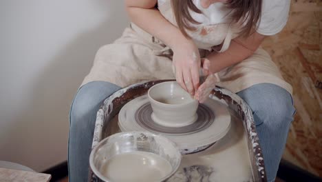 woman shaping a bowl on a pottery wheel