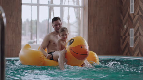 Un-Niño-Lindo-Y-Su-Padre-Están-Montando-Un-Divertido-Pato-Inflable-En-La-Piscina-Divirtiéndose-Y-Descansando-Juntos