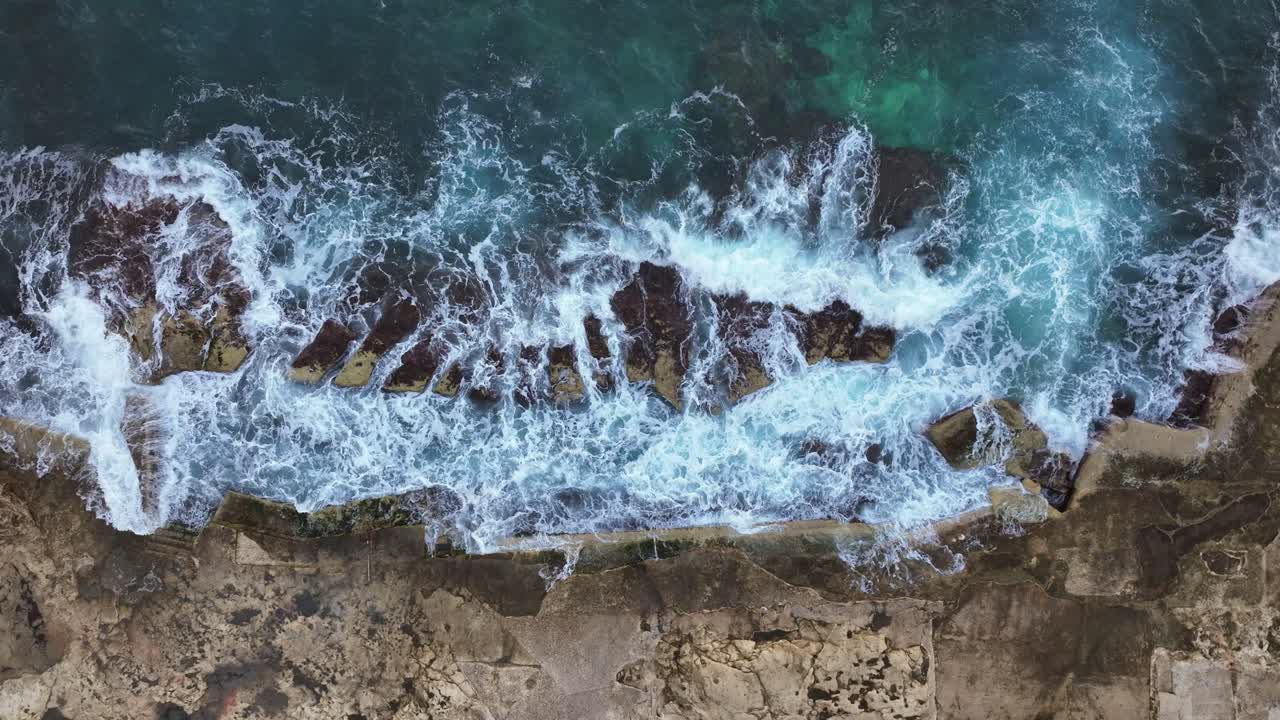 Vista dall'alto su una costa rocciosa a Malta, con onde che si infrangono