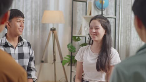 close up of asian teen group sitting in chairs forming a circle discussing at home. celebrating, applause or audience clapping hands after a girl giving speech