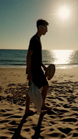 Man walking on the beach at sunset carrying art supplies