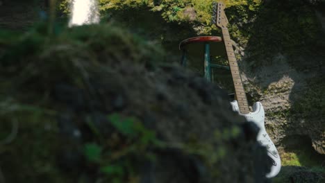 Hombre-Tocando-La-Guitarra-Frente-A-Una-Hermosa-Cascada-En-Islandia