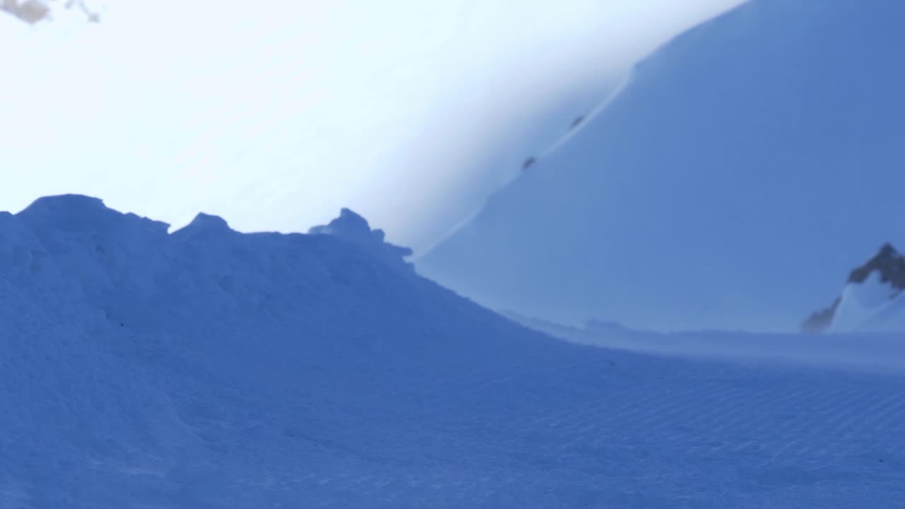 Heavy snowstorm wind blowing over snowy mountains high in the alps - static view
