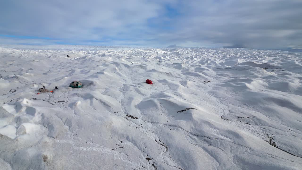 Low flyover of vast glacier toward tent camp set up for eco-tourism