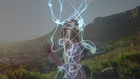 Creating animation of glowing light trails, person outdoors in mountainous landscape