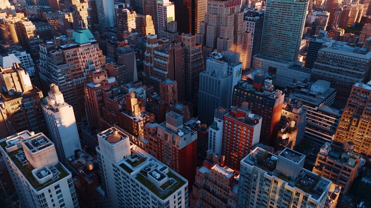 Vista dall'alto di densi edifici residenziali e per uffici. Prospettiva dall'alto dell'architettura urbana con varie tessiture dei tetti e torri d'acqua alla luce del tramonto.