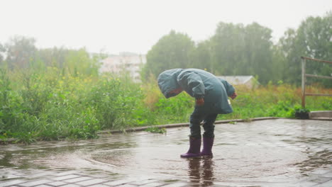 niño jugando en un charco en un día de lluvia