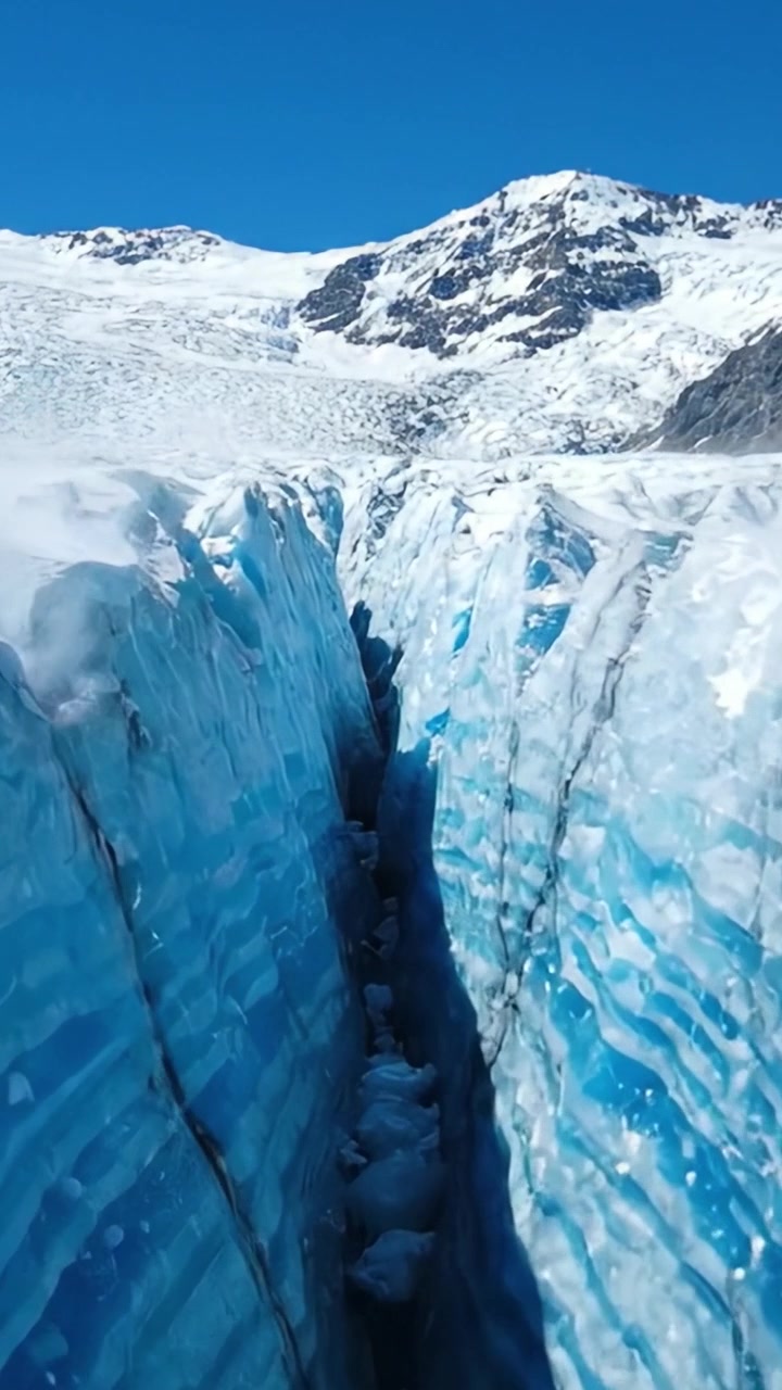 Maestoso crepaccio glaciale: viste mozzafiato di formazioni di ghiaccio blu intenso e cime innevate sotto cieli sereni.