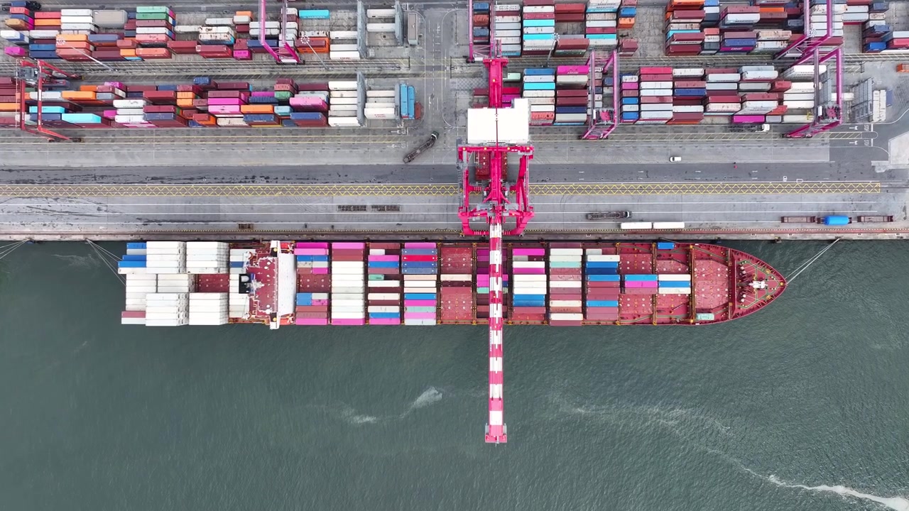 Large container ship arrives at the terminal, surrounded by colorful shipping containers. Workers and cranes are busy unloading cargo. This scene showcases the heart of international trade.