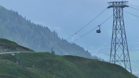 occupants being transported by cable cars above green mountainous landscape