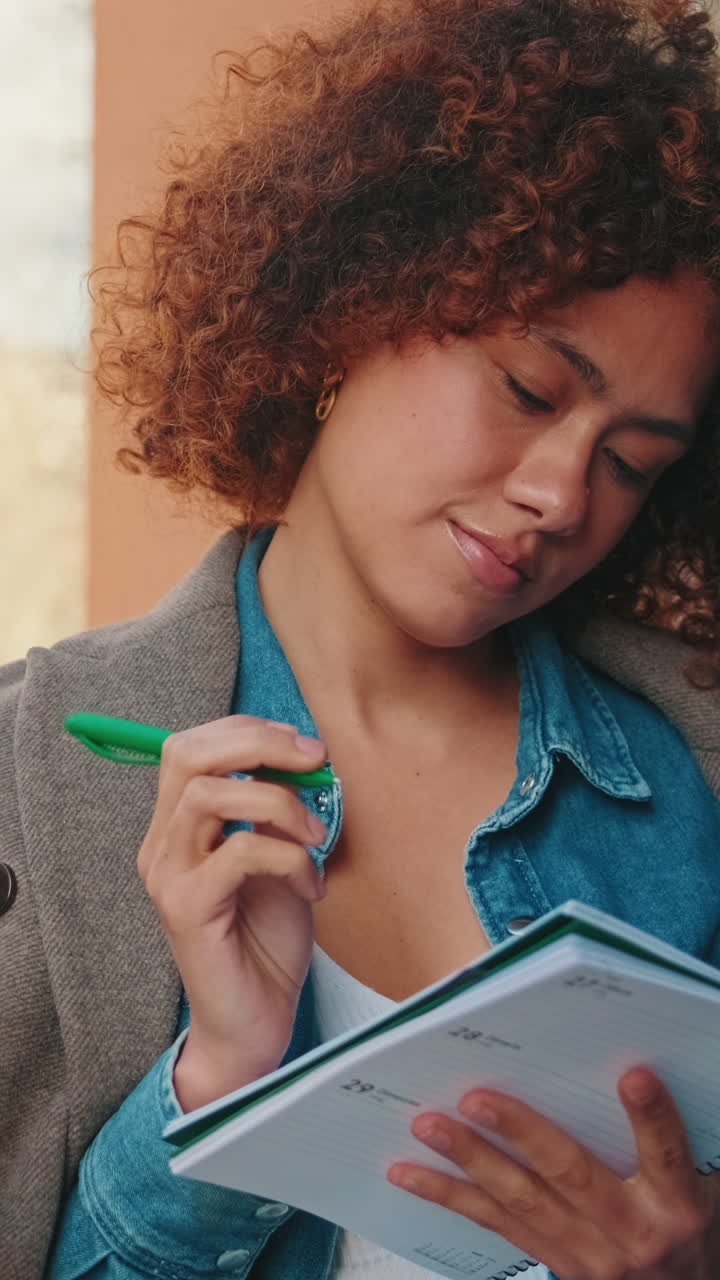 Thoughtful Young Woman Writing Notes in a Notebook