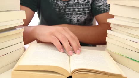 estudiante masculino leyendo un libro sentado entre pilas de libros 1