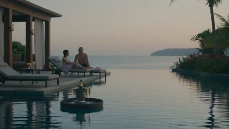 serene evening by the infinity pool: a couple enjoys a romantic sunset in a luxurious resort setting, with tranquil waters and lush tropical surroundings