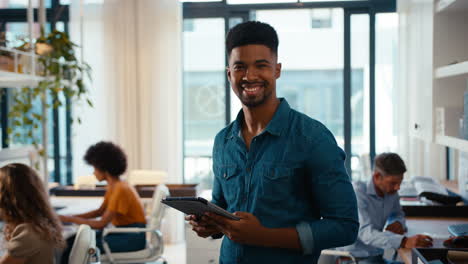 portrait of young smiling businessman with digital tablet standing and working in modern office