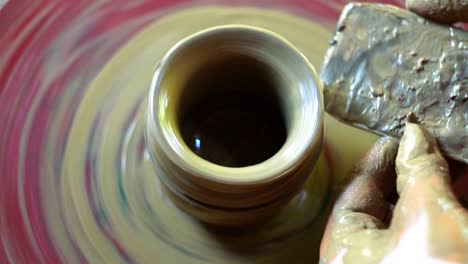 dirty hands making pottery on wheel spinning top view close up