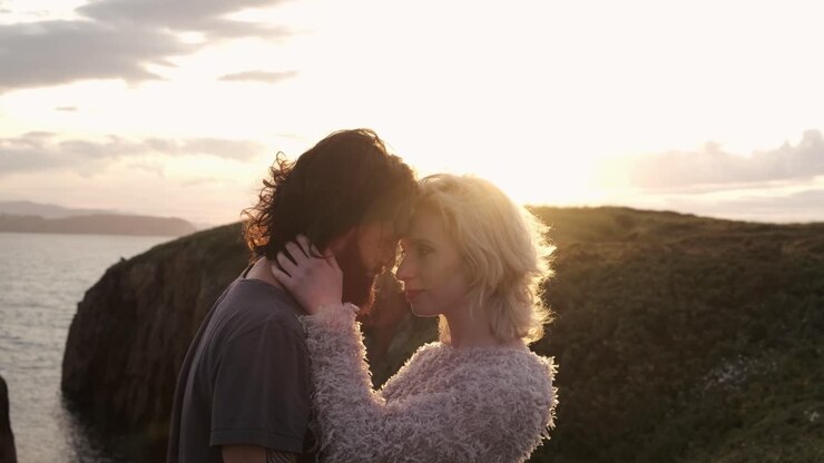 Couple s'étreignant sur fond de coucher de soleil.