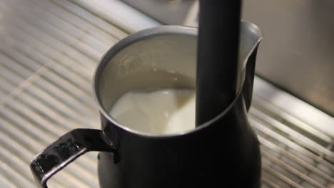 frothing milk with steam wand from espresso machine close up