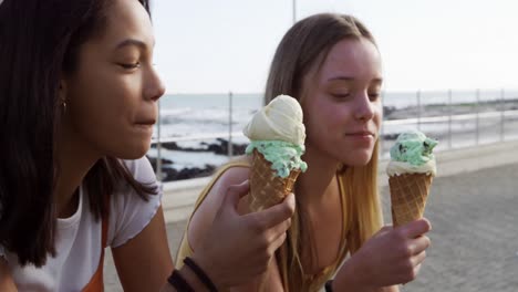 Vista-Lateral-De-Una-Chica-Caucásica-Y-De-Raza-Mixta-Comiendo-Helado-Junto-Al-Mar