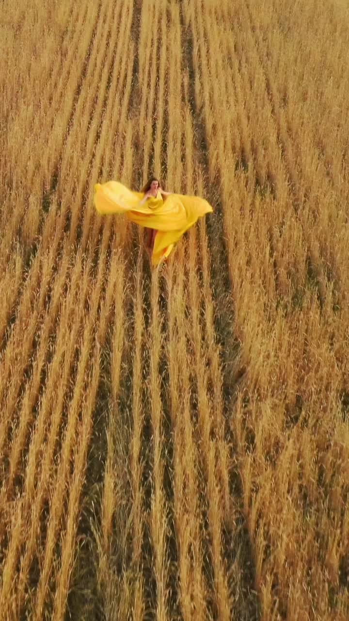 Woman in a yellow dress running through a golden wheat field
