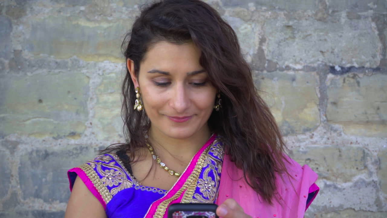 Ragazza che messaggia con il cellulare e il vento le muove i capelli