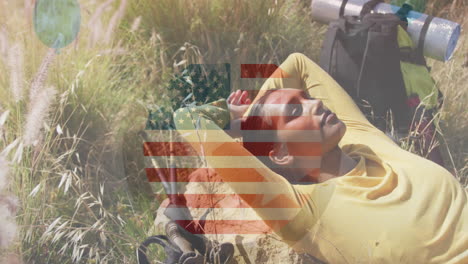 animation of american flag over biracial woman lying in mountains