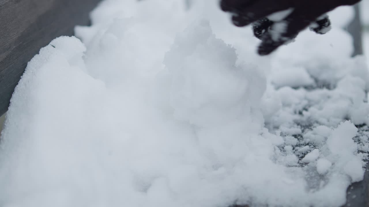 Slowmotion closeup of preparing pile of snowballs with black gloves