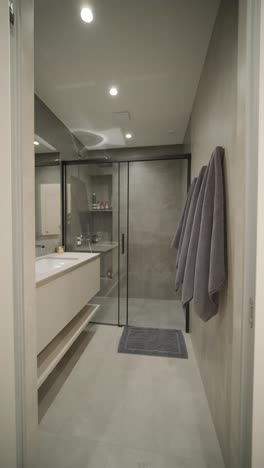 modern minimalistic bathroom interior design with grey stone tiles, black furniture, eucalyptus in glass vase, round mirror. aesthetic simple interior design concept.