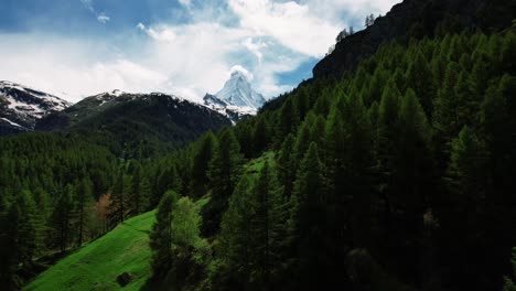 drone de 4k volando sobre árboles verdes y exuberantes hacia la nieve cubierta de la montaña matterhorn en zermatt, suiza