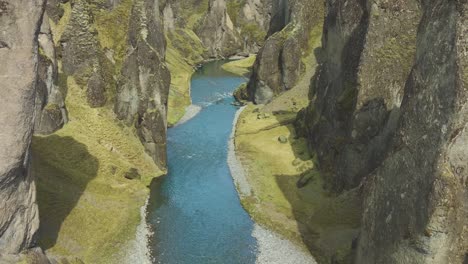 Clear-river-flows-through-imposing-scenic-Fjadrargljufur-canyon,-Iceland