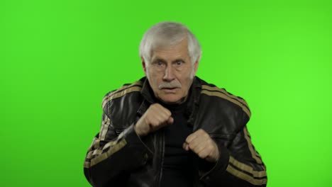 anciano abuelo caucásico hombre rocker muestra pelea de puños. fondo clave de croma