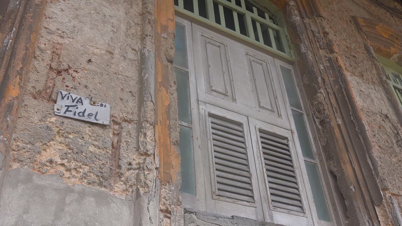 Vecchie finestre fatiscenti su un edificio all'Avana, Cuba, con un'insegna che recita "Viva Fidel".