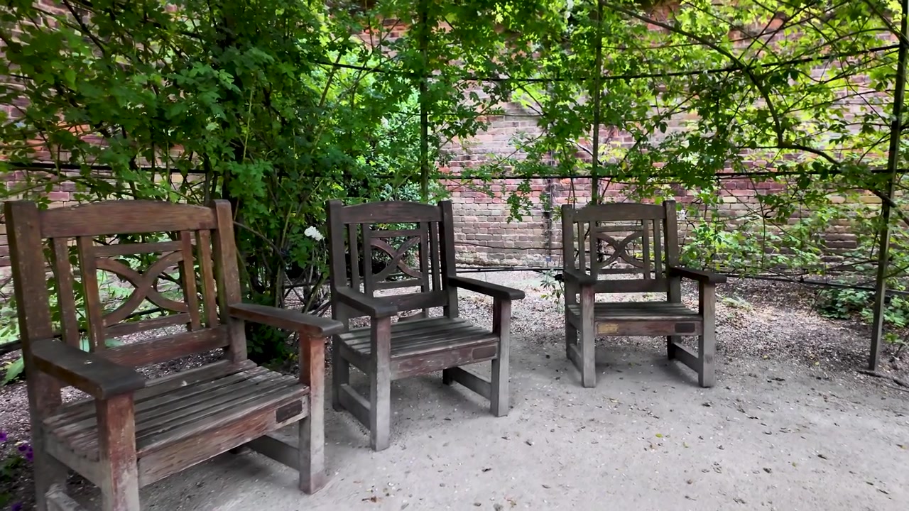 Tre sedie di legno vuote posizionate in un giardino verde tranquillo e rilassante, in attesa di qualcuno